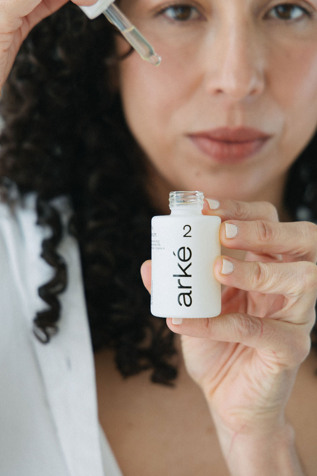 Woman holding arke serum with eyedropper coming out of bottle