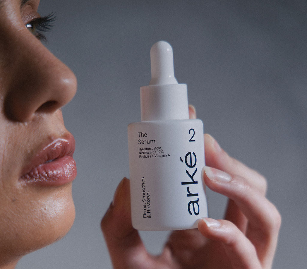 Woman holding arke serum with a neutral background