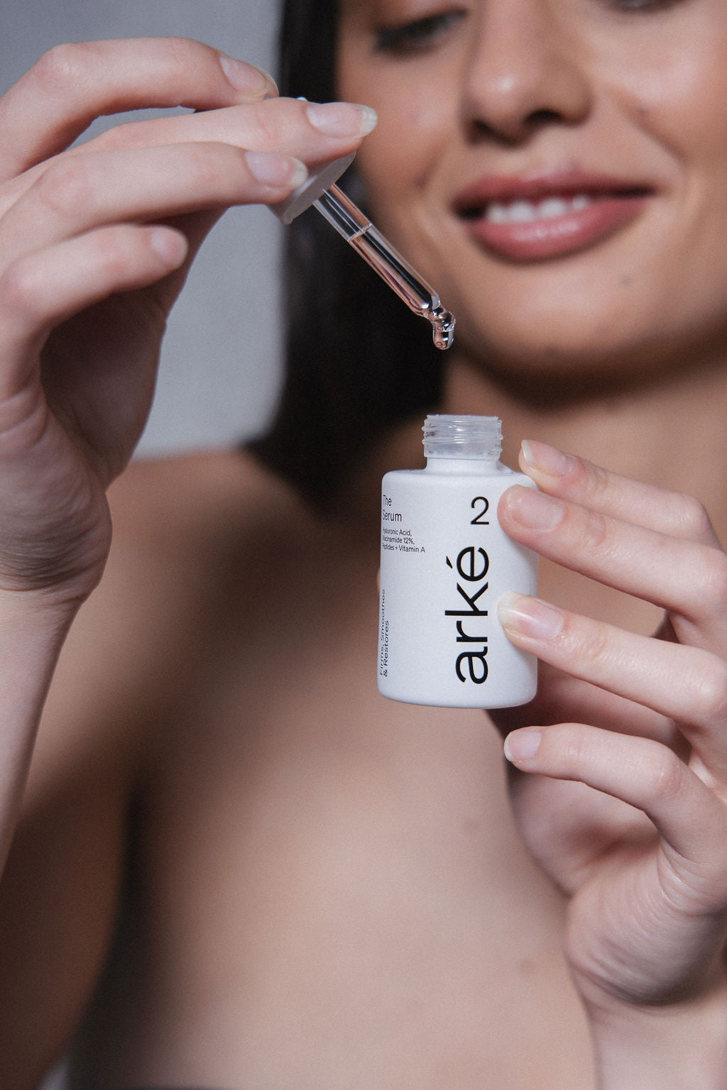 Woman holding arke serum with eyedropper coming out of bottle